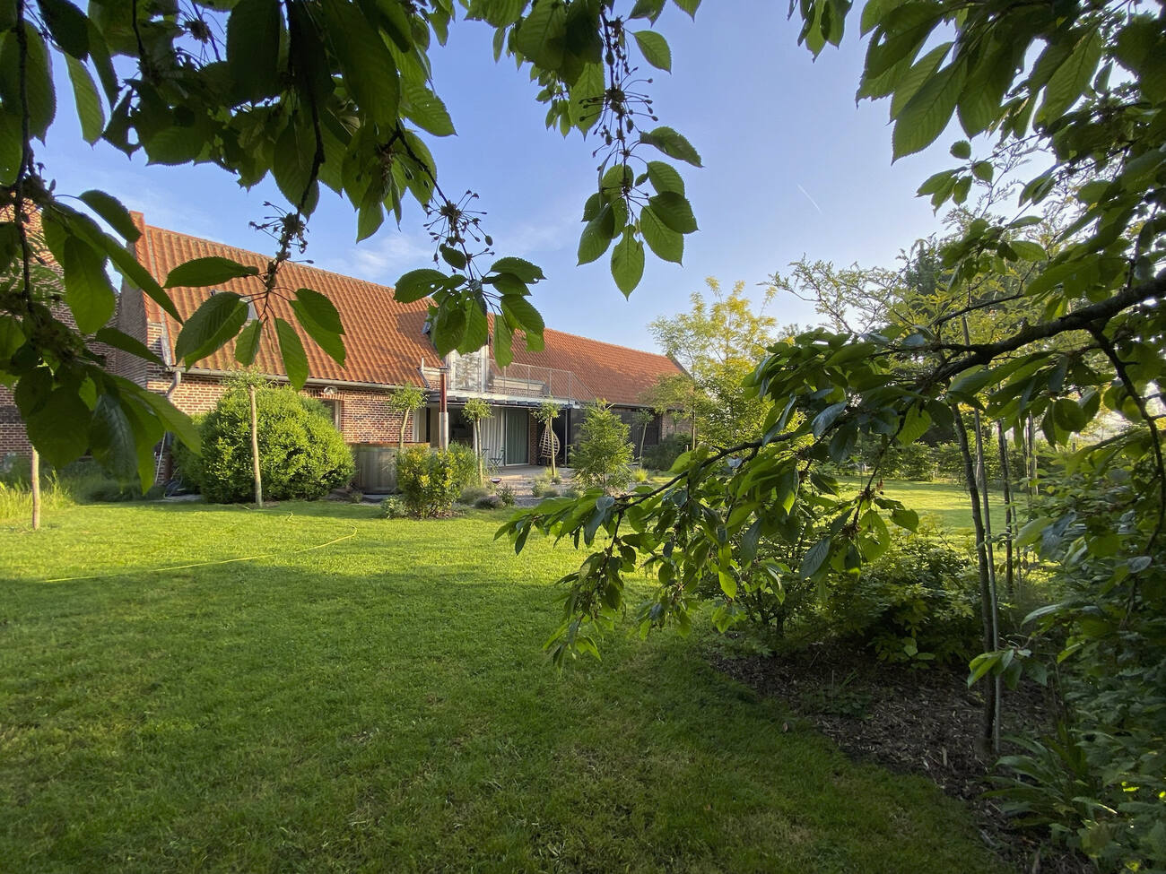 Le jardin arboré et l'ancienne ferme au carré du gîte Au Milieu Du Jardin