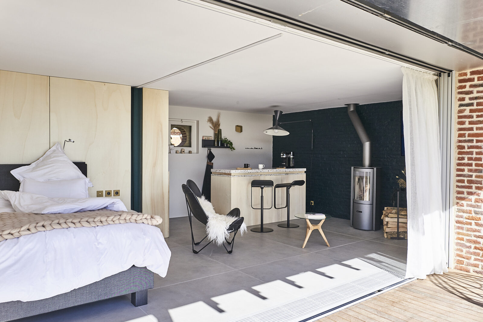 Vue d'ensemble de la Suite Nordique : chambre ouverte sur la cuisine et le poêle à bois