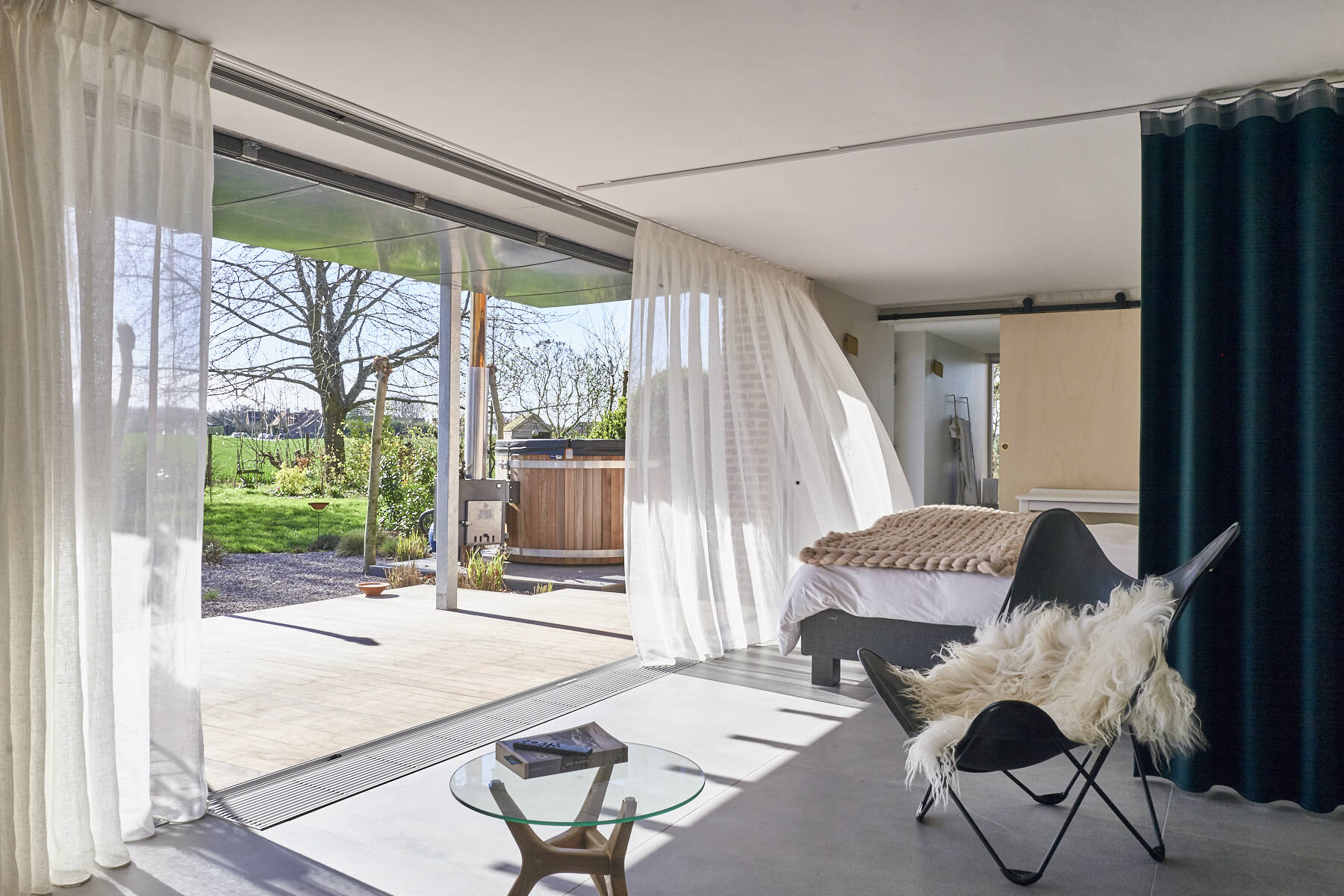 La Suite Nordique ouverte sur la terrasse, le bain nordique et le jardin en été