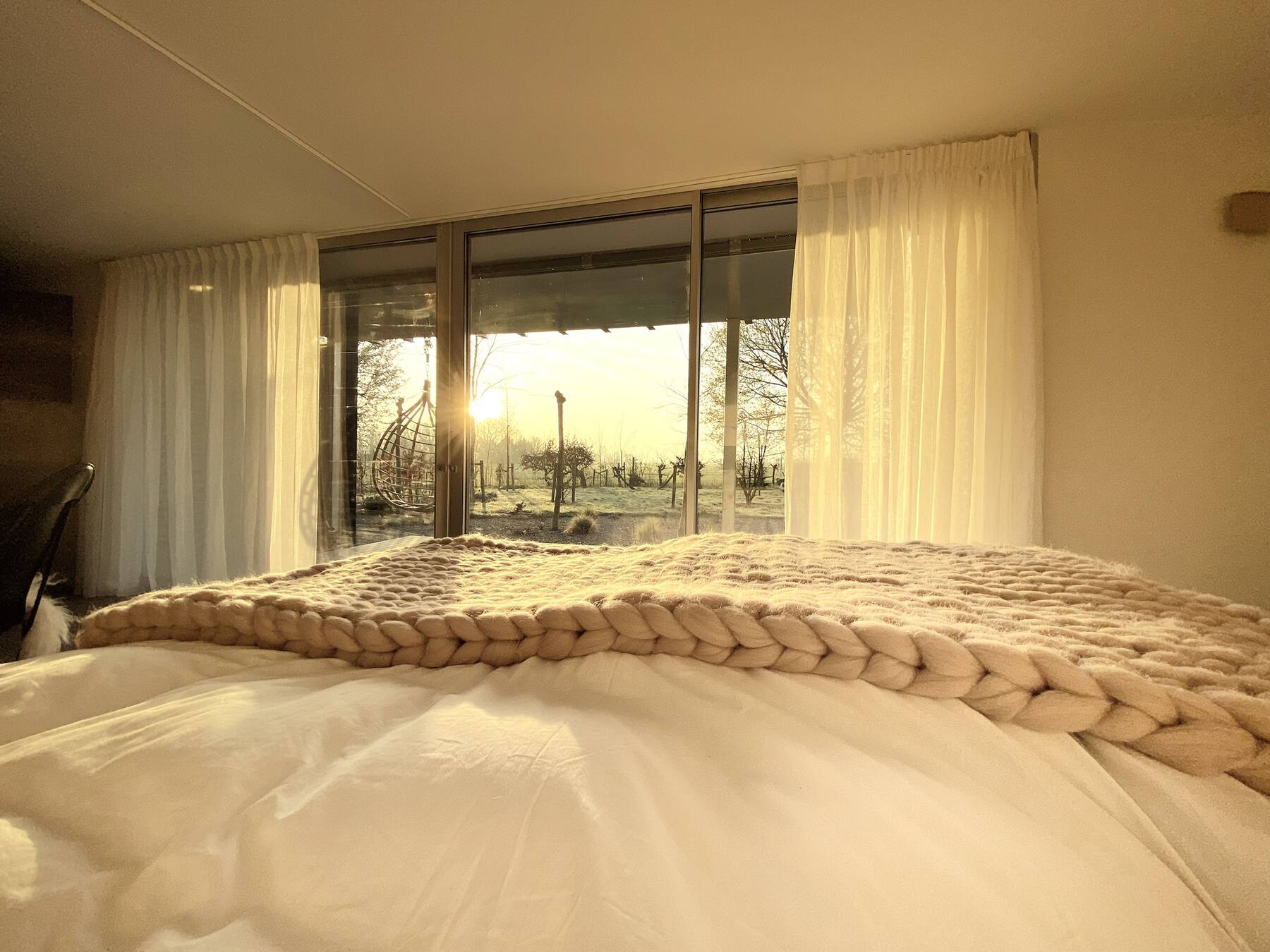 La chambre de la Suite Nordique face au lever de soleil givré, en hiver